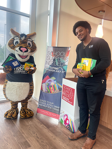 TigerSquirrel and Tigers Employee Roman standing with the School Supply Drive set up in the branch.